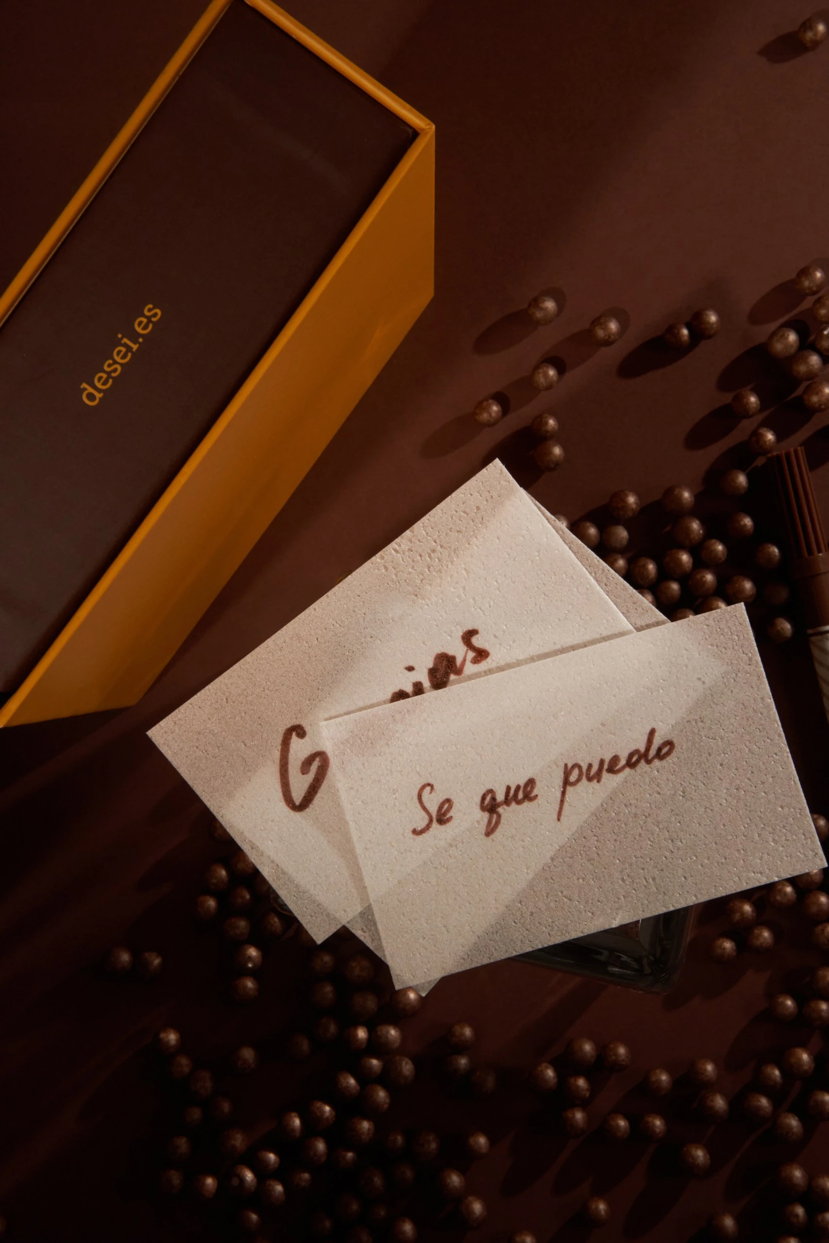Obleas comestibles con los mensajes «Gracias» y «Sé que puedo» junto a la caja DESEI y perlas de chocolate