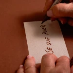 Primer plano de una mano escribiendo un mensaje en oblea con rotulador comestible